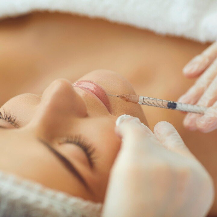Woman receiving lip filler in brightly lit room